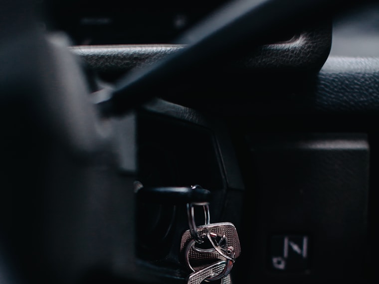 A key sitting in a car ignition cylinder, lit from one side in near darkness